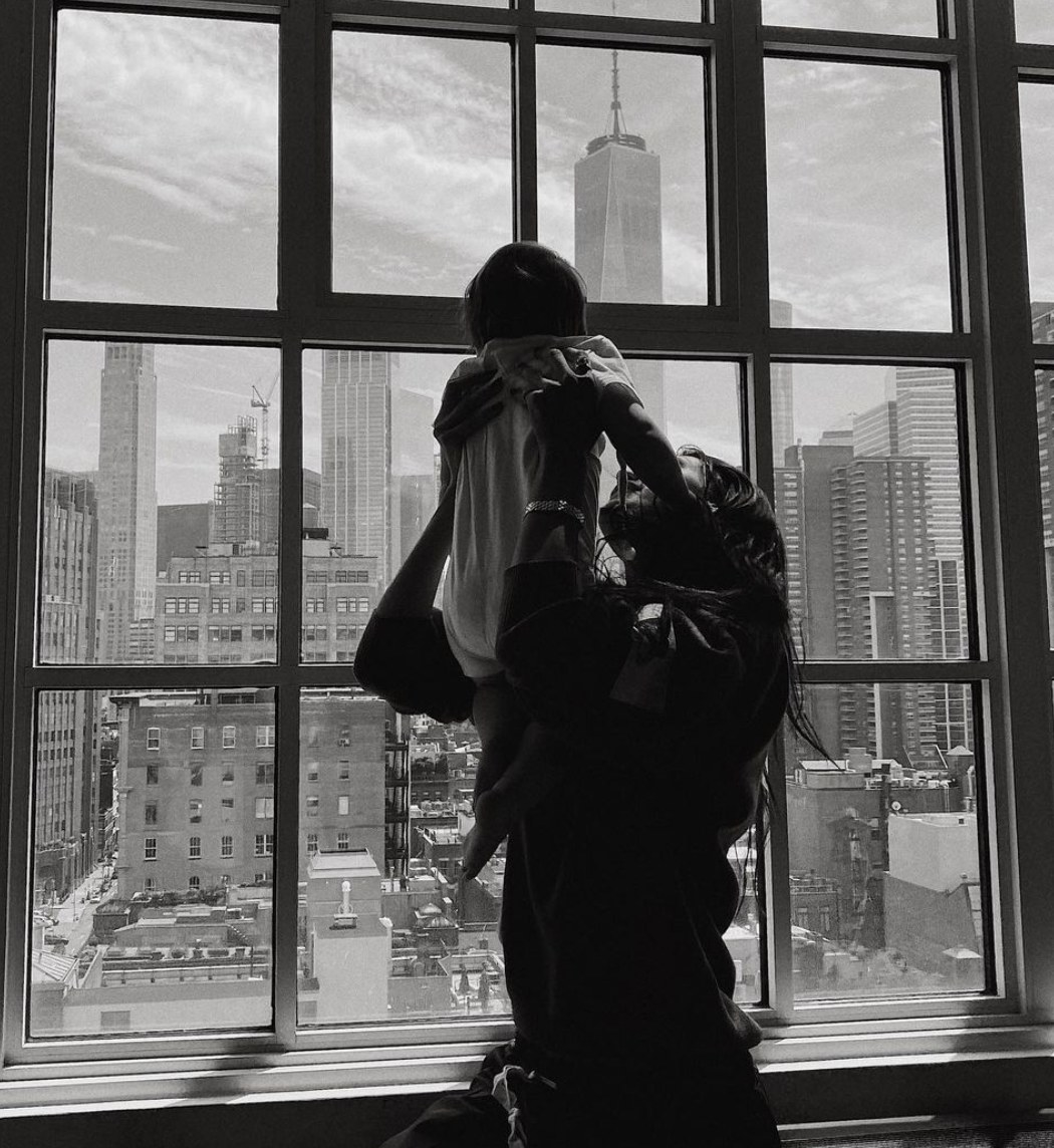 A black and white photo of Bella holding Khai in the air