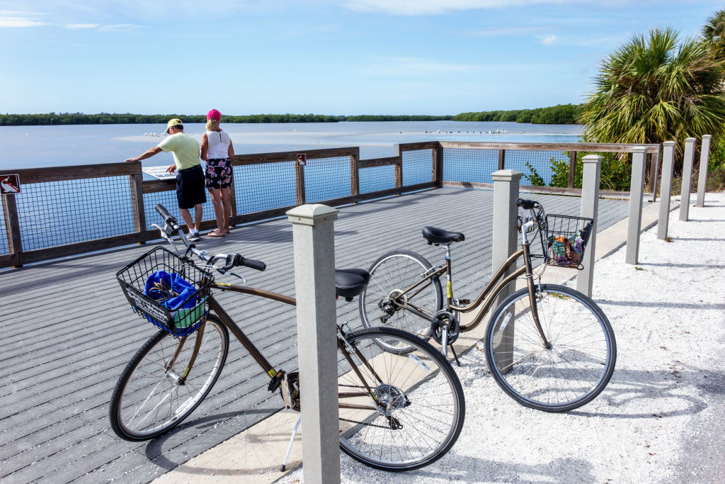 Two people looking out at water with two bikes parked on the pier behind them