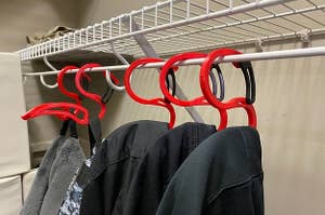 Five hoodie hangers hanging in a closet with hoodies on them