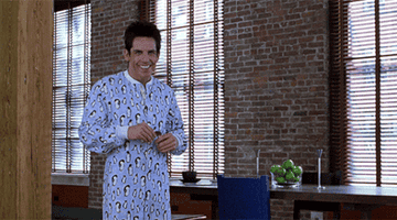 Gif of Zoolander in a onesie smiling and flailing his arms in a friendly way