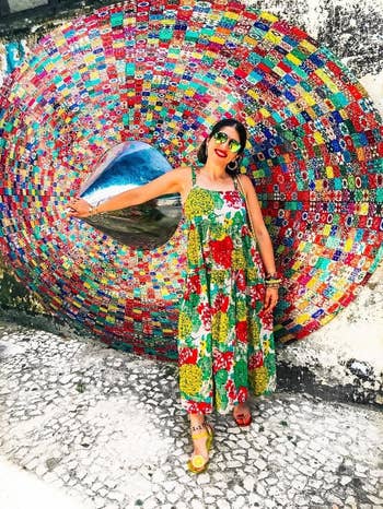 image of reviewer wearing multicolored floral maxi dress in front of a colorful mosaic wall
