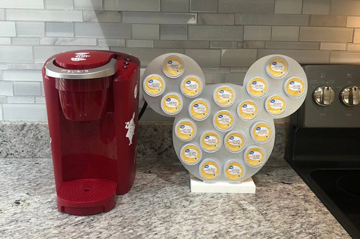a silver mickey-shaped k-cup holder next to a keurig machine