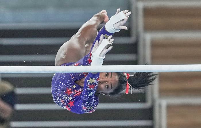 Simone Biles reaching for the uneven bars