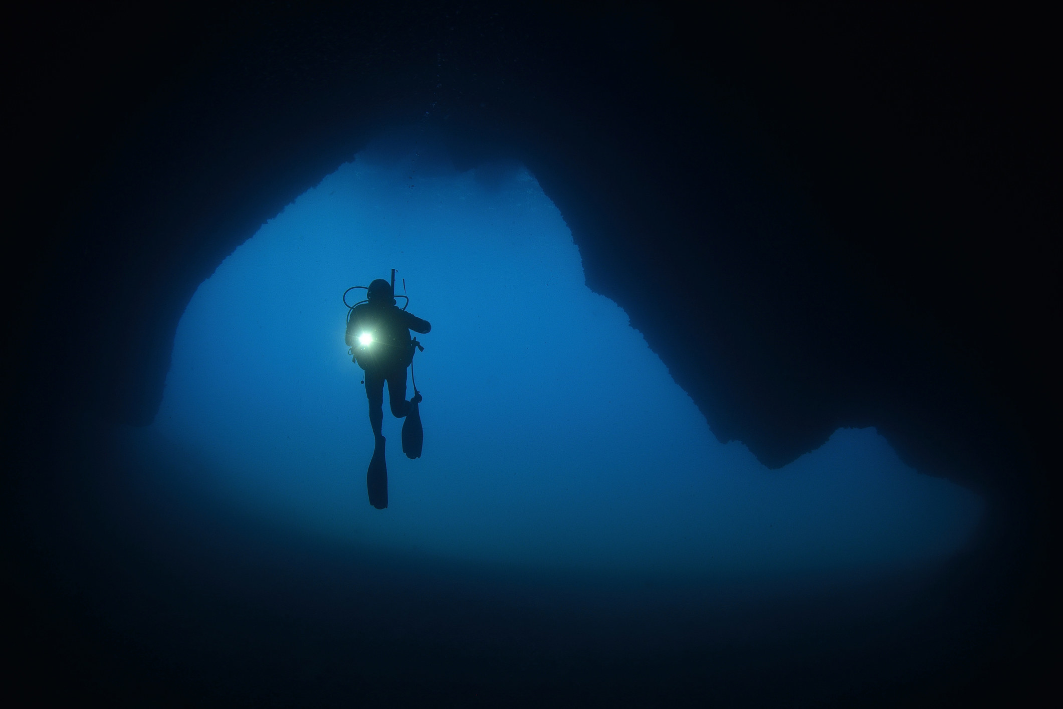 Someone cave diving in a dark underwater cave