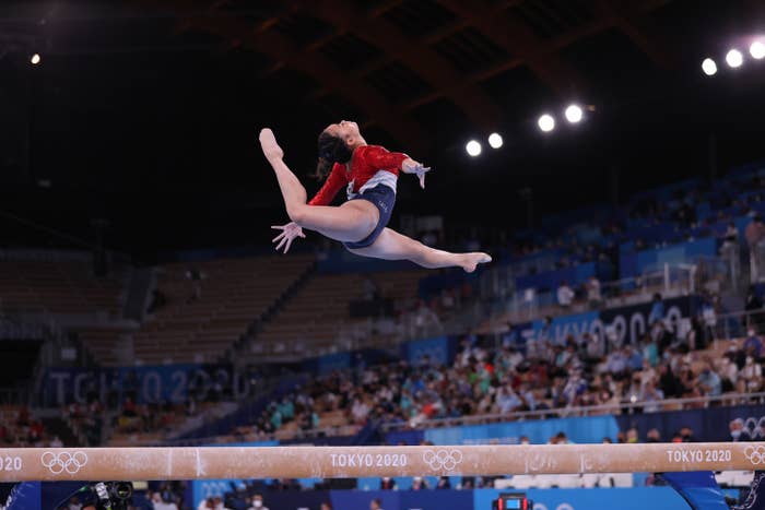A gymnast in a full split high over the balance beam