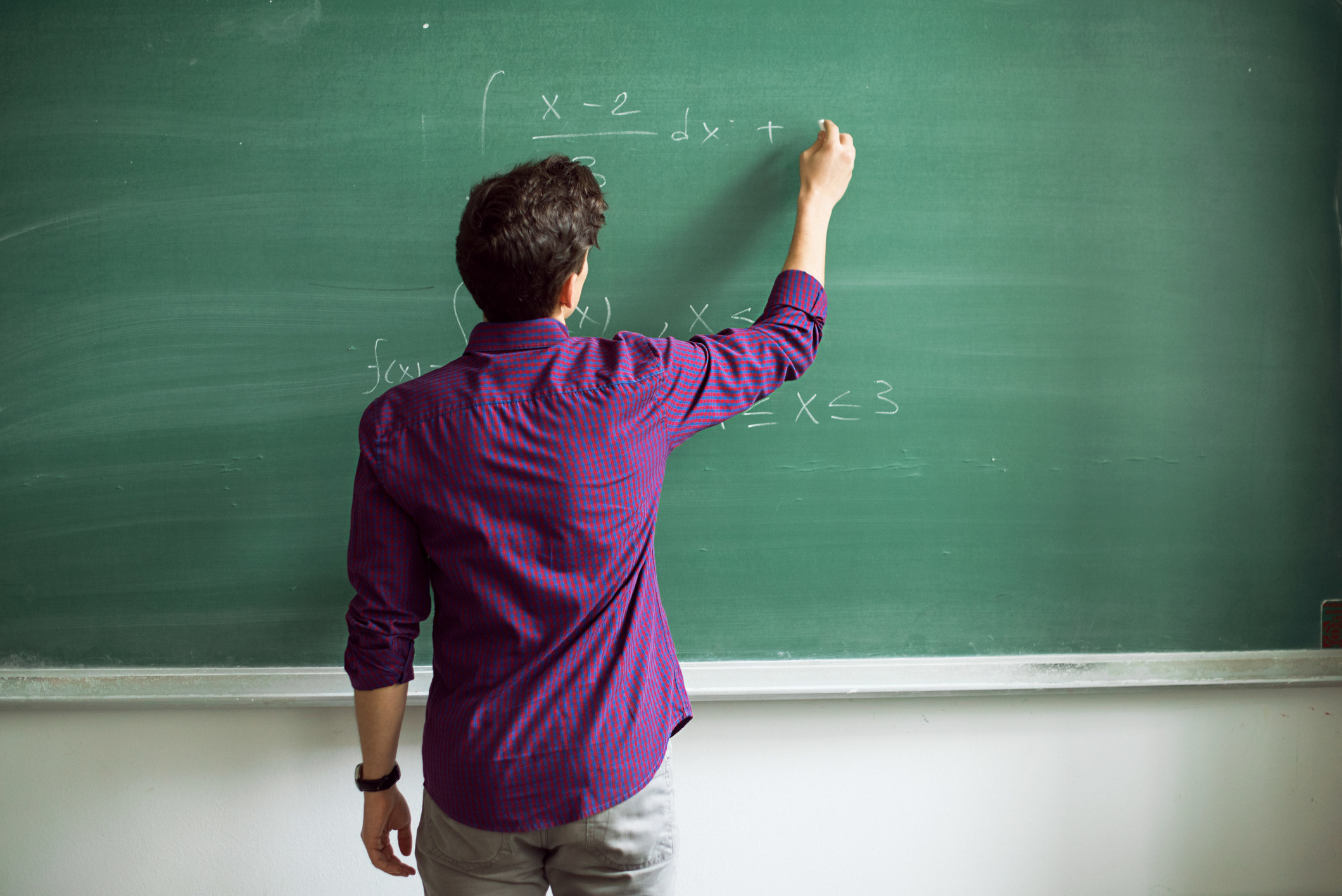 teacher writing math equations on a chalkboard