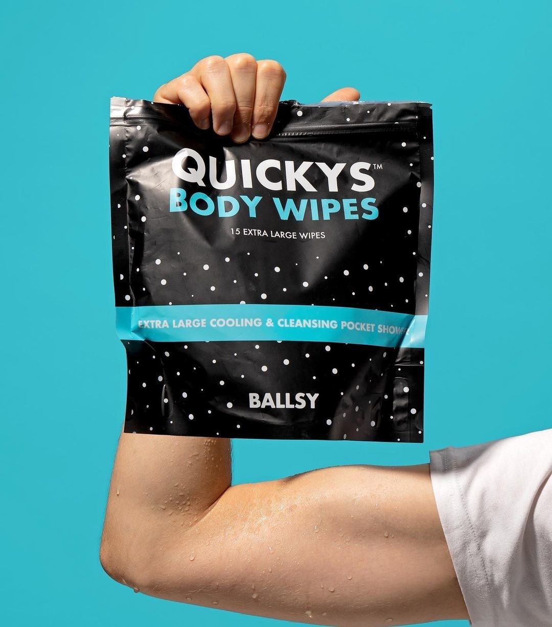 Someone holding up a pack of the body wipes while flexing their bicep