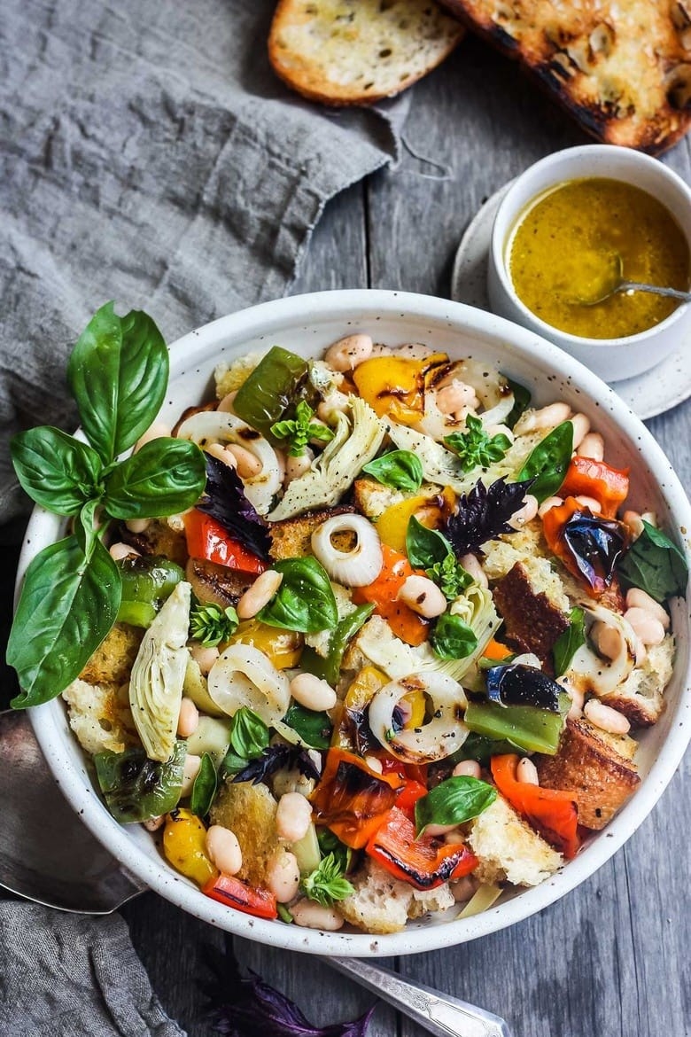 a salad with peppers, basil, white beans, onions, artichokes, and more