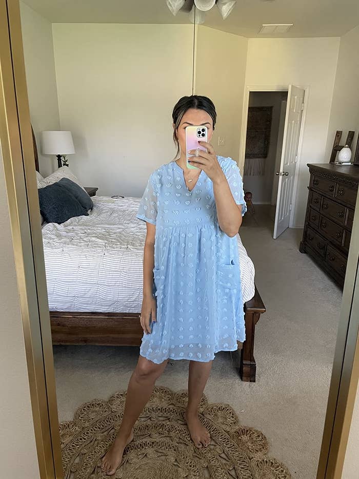 mirror selfie of a reviewer wearing the light blue short sleeve pom pom dress