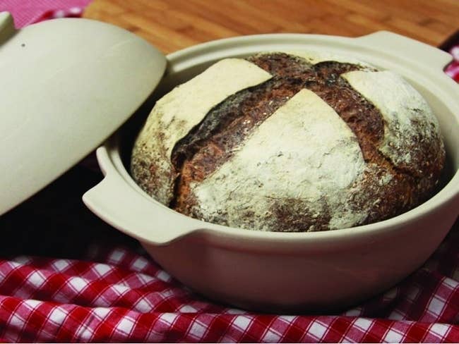 Baked bread inside a bowl with handles and a lid