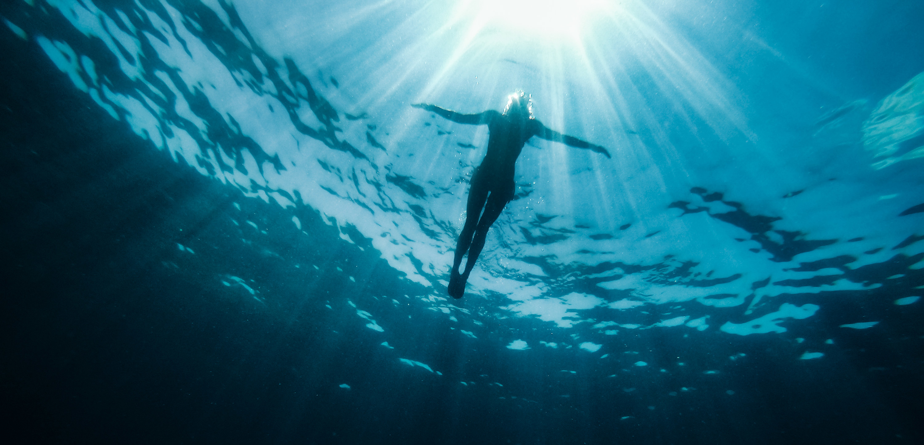 Underwater photo of woman floating in the sea and rays of light piercing through