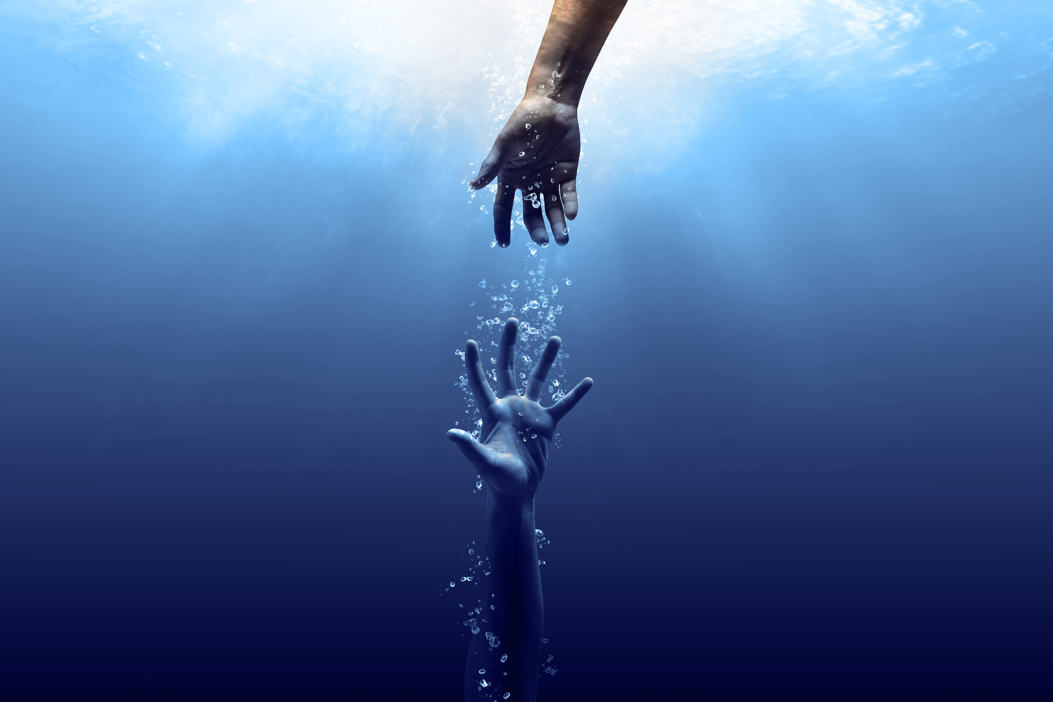 A hand reaching for another hand underwater