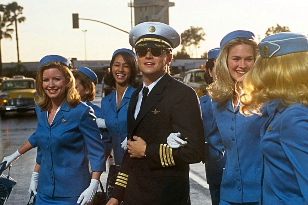 leonardo dicaprio as frank, dressed as a pilot flanked by flight attendants