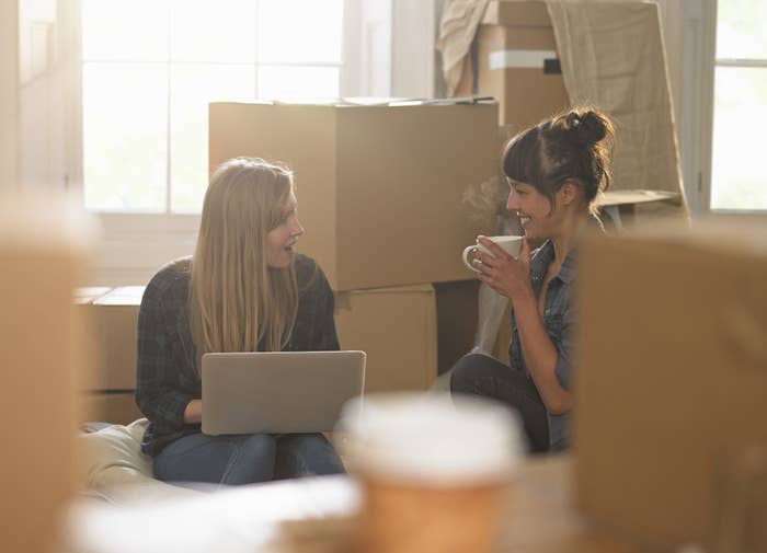 Young roommates surrounded by boxes in their new apartment