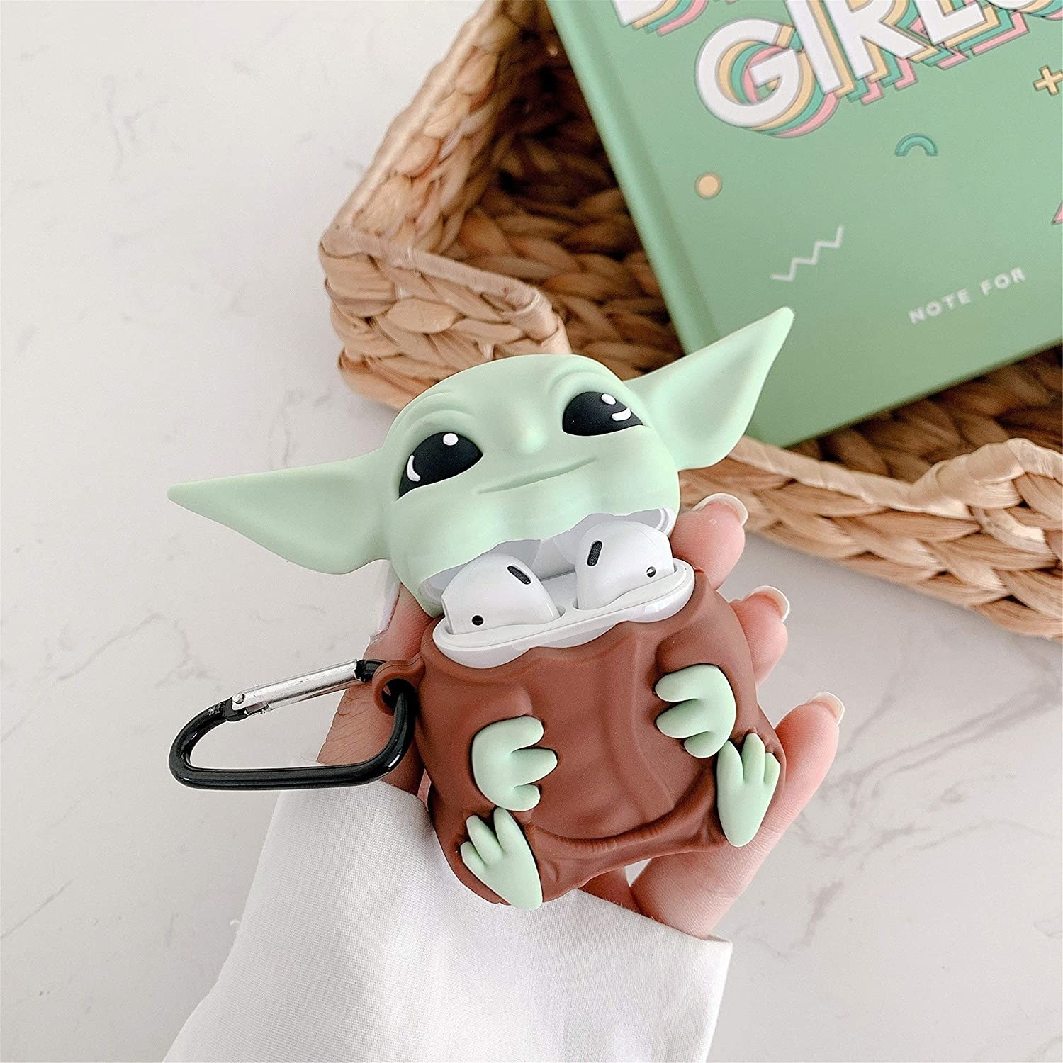 An Airpods case with a silicone skin over it that looks like Baby Yoda