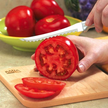 Person slicing large tomato with knife 