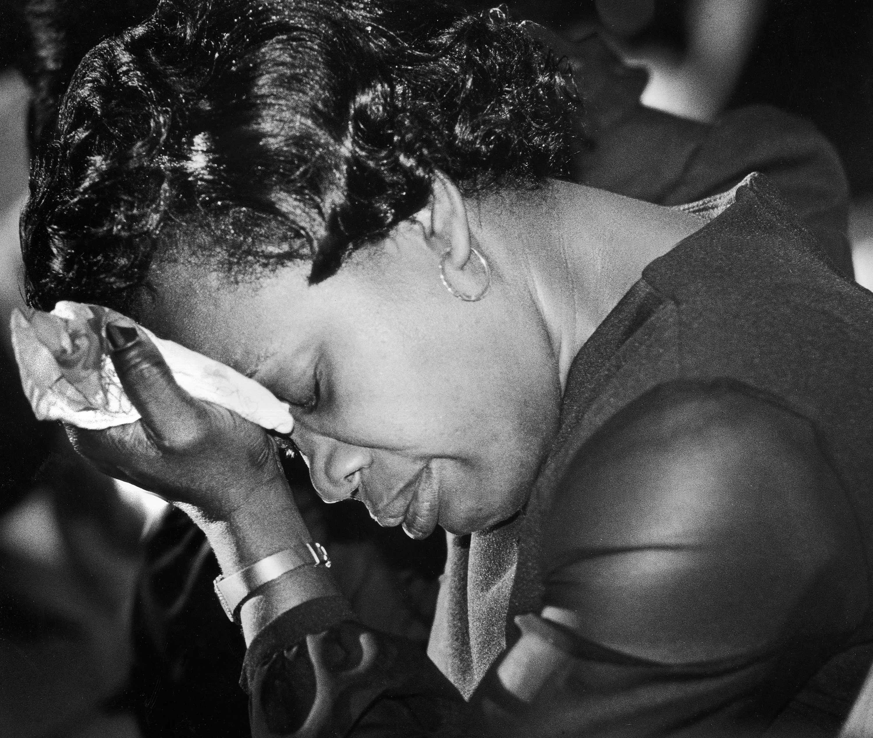 Mourner at funeral for Haitian drowning victims holds her head in her hand