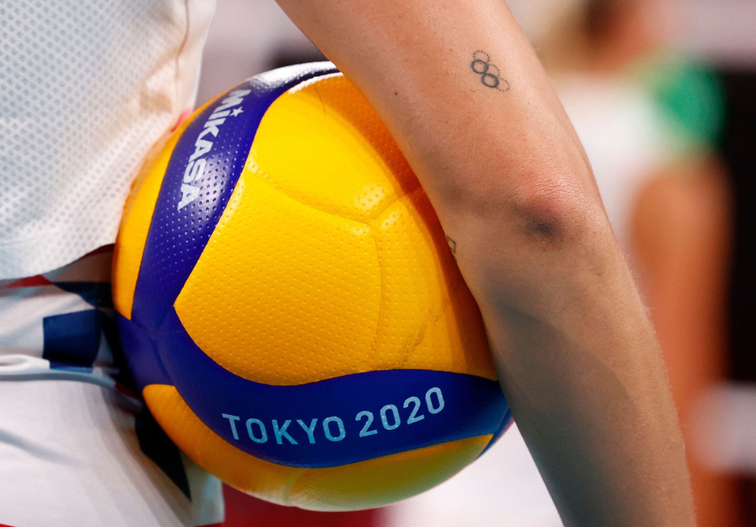 Bright yellow Tokyo 2020 ball is held under the arm of an Olympic athlete