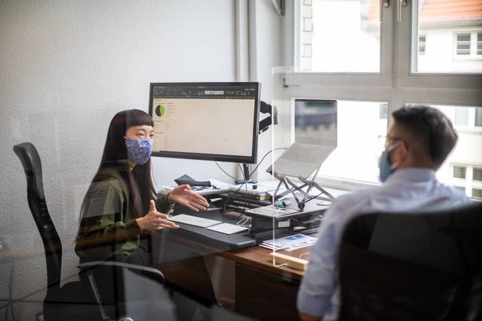 Office workers wearing masks and using glass partitions between their desks