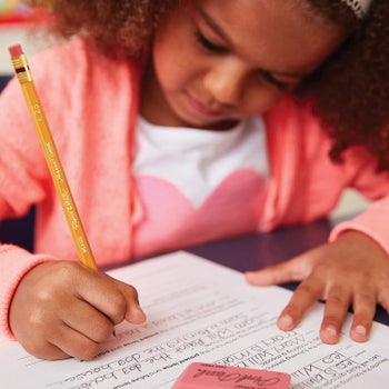 A child working on an assignment with a pencil and a pink eraser