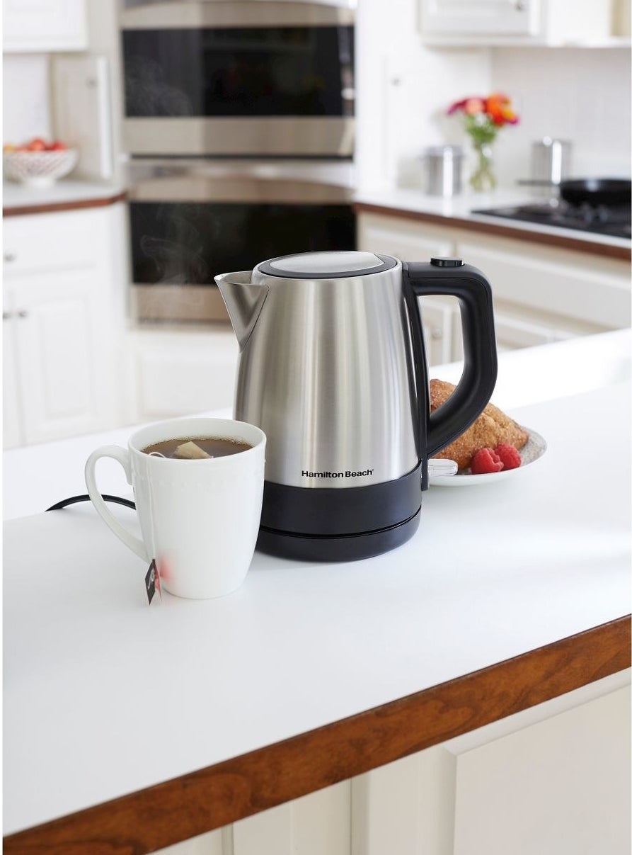 the electric kettle sitting on a counter next to a cup of tea