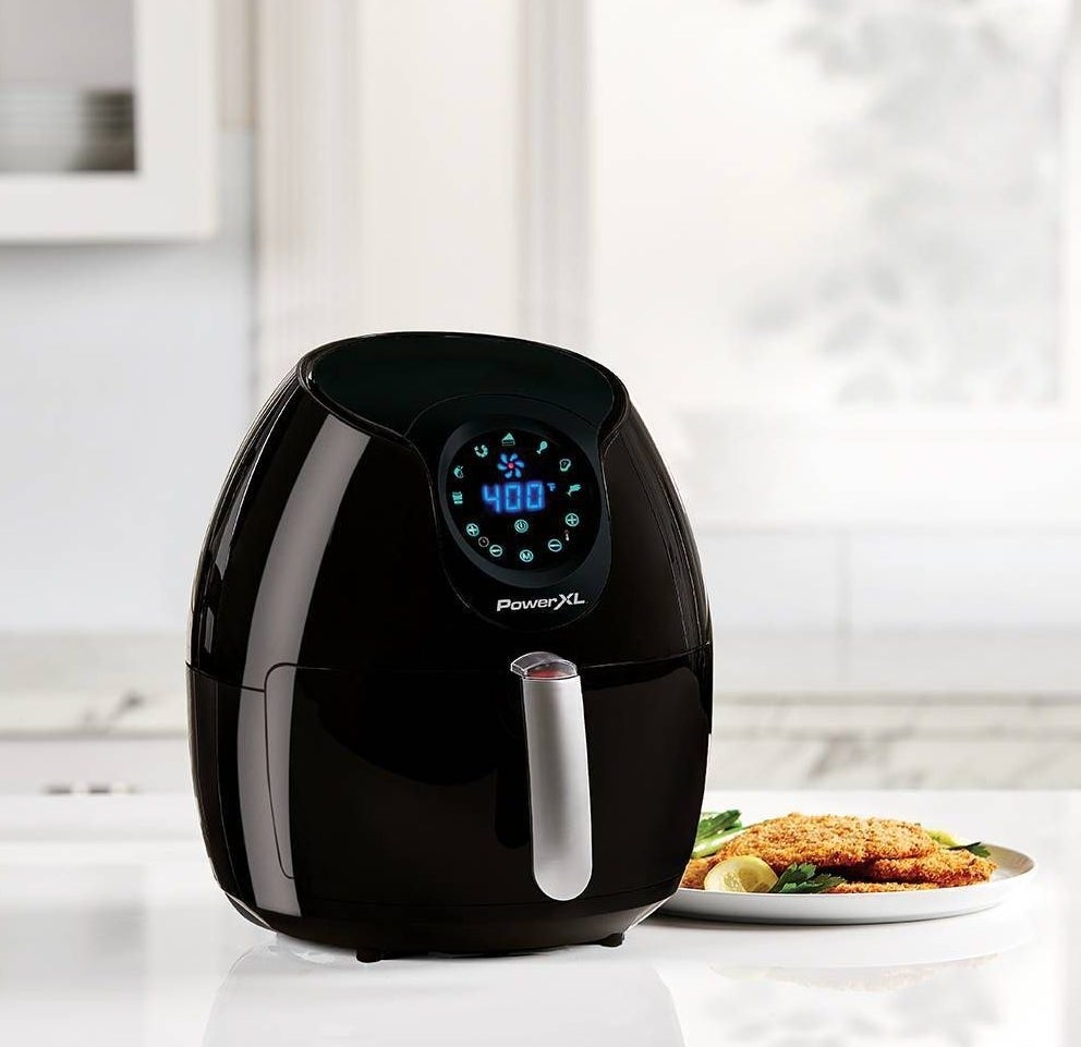 the air fryer on a counter next to recently air-fried chicken