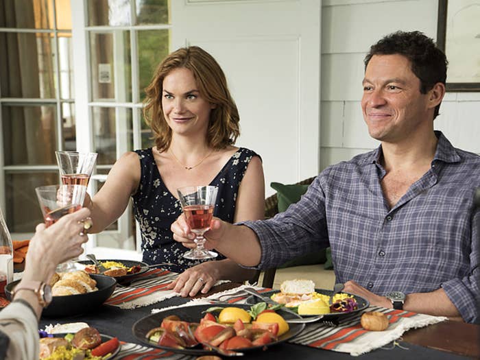 Ruth Wilson and Dominic West raise glasses at a table