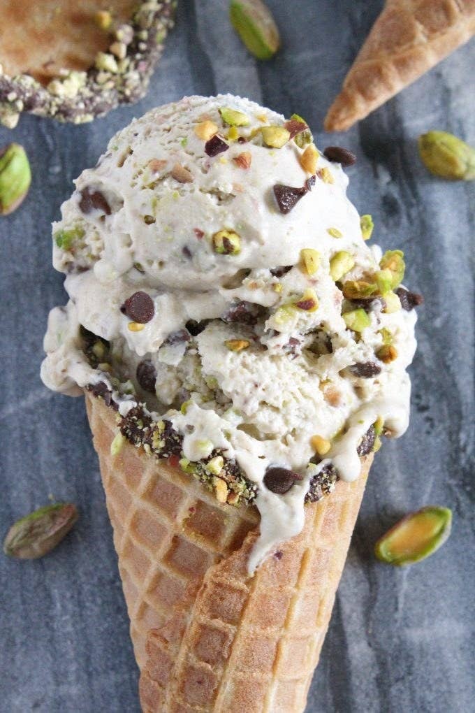 Cone of pistacchio gelato with specks of crunchy chocolate chips and pistachio bits