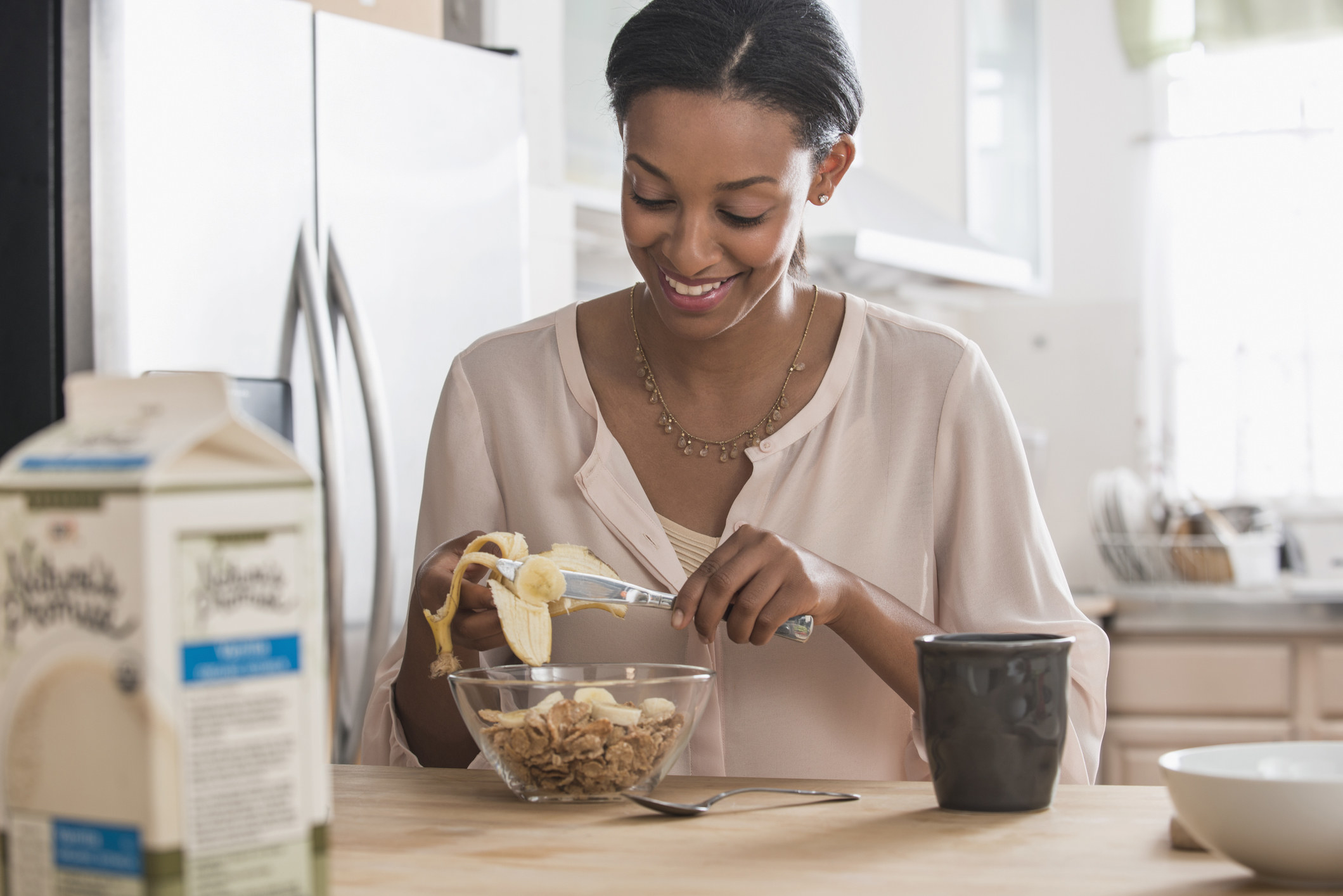 woman chopping a banana into her cereal