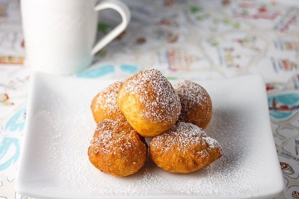 Sugar-dusted, plushy zeppole on a square white plate