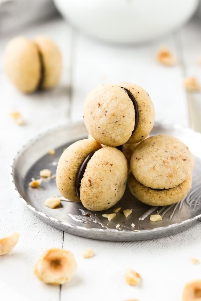 Three tiny cookie sandwiches made up of two dome-shaped hazelnut-specked cookies and a chocolate filling