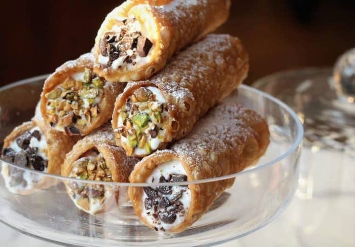 A pyramid of cannoli filled with ricotta cream and studded with chocolate and crushed pistachio pieces