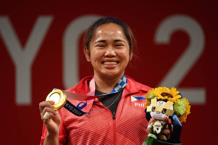 Hidilyn posing for photos with her gold medal and flower bouquet