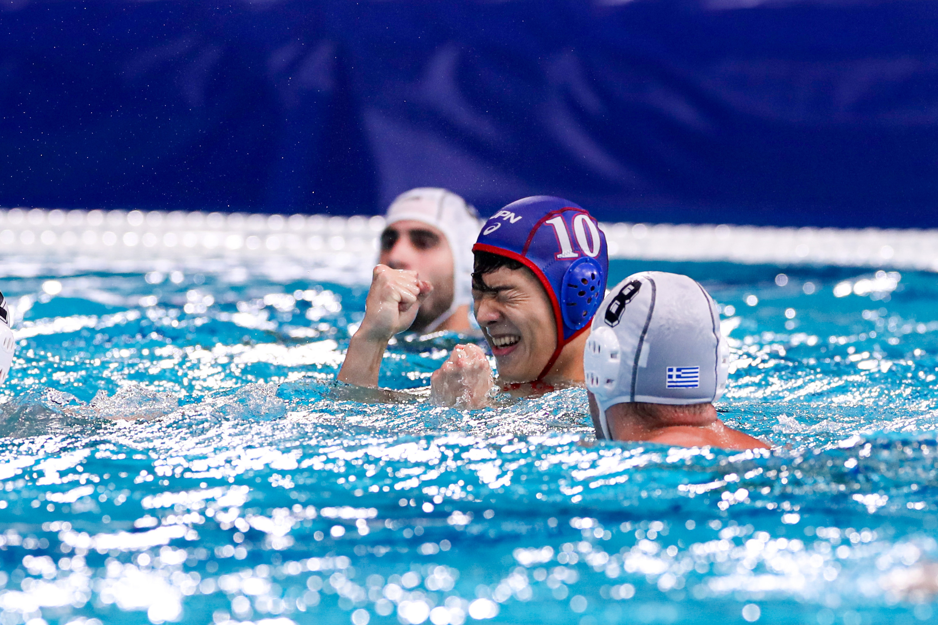 A water polo athlete celebrates with eyes closed and fists up in a pool