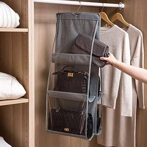 Someone putting a clutch purse into one of the transparent pockets on the hanger