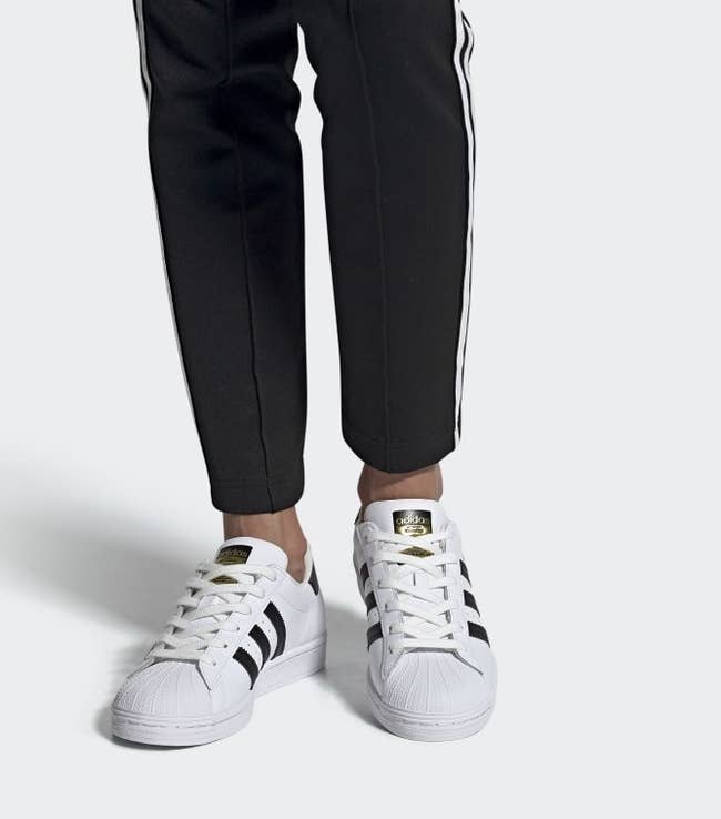 model wearing black and white superstar adidas shoes