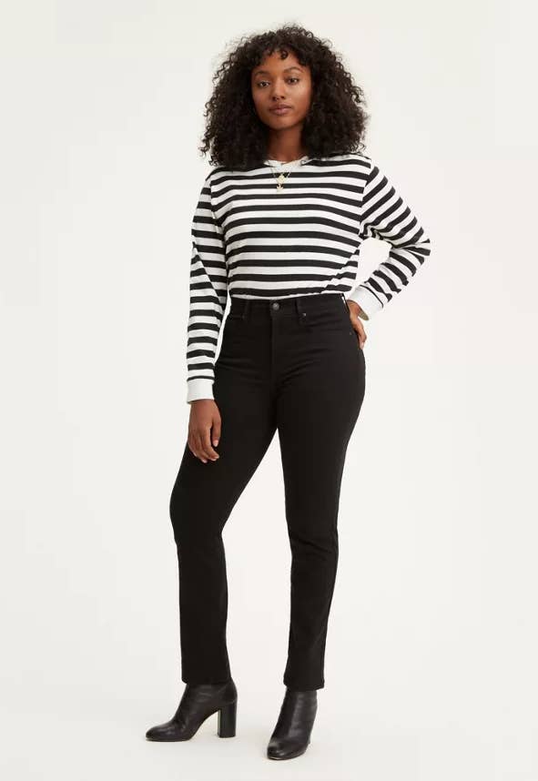 model wearing a pair of black straight jeans with a black and white striped shirt and black heeled booties