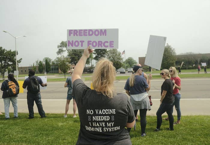 A anti-vaccine protester holding a placard saying, "Freedom not force"