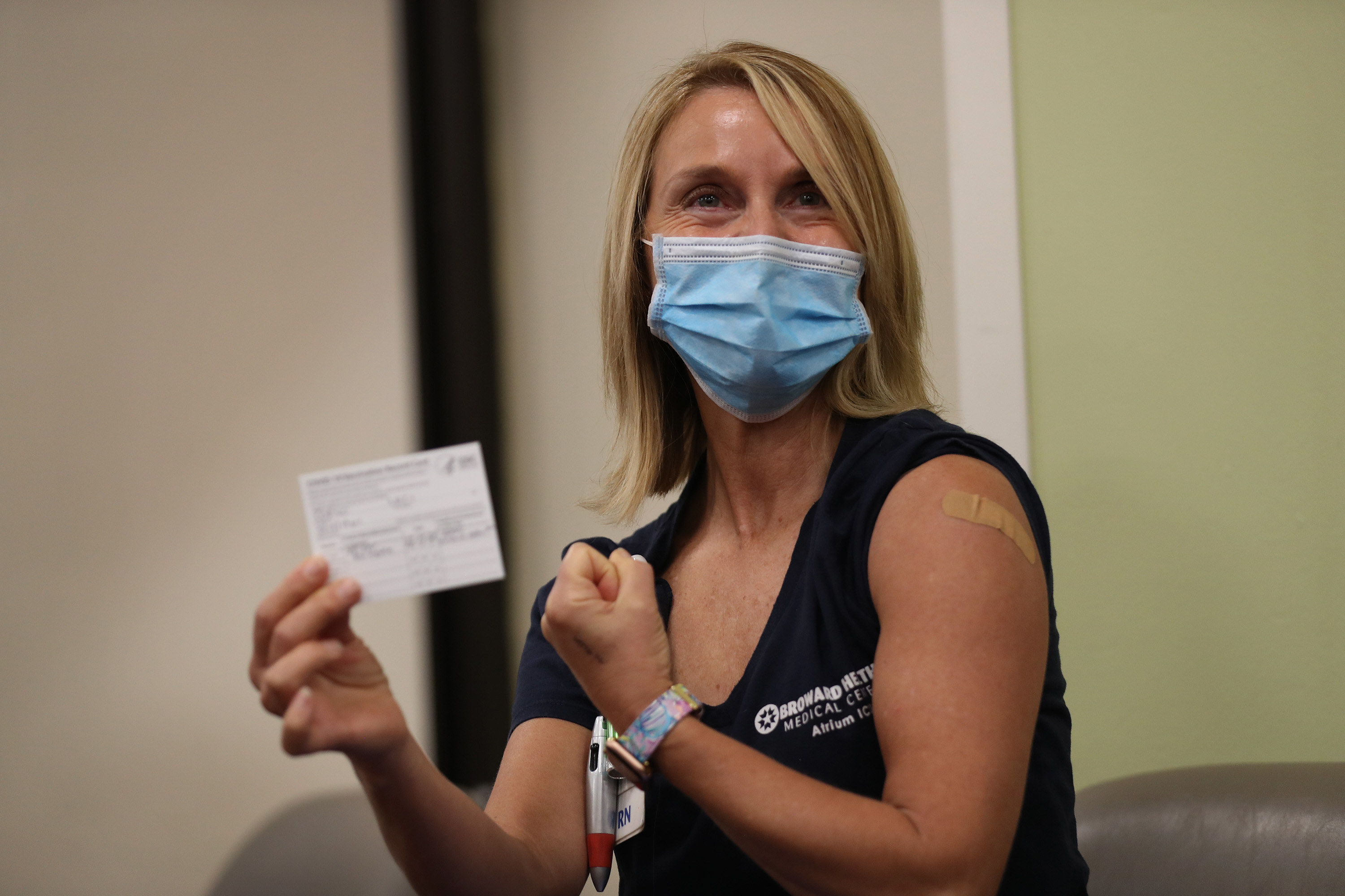 Nurse flexes her arm as she shows off her COVID-19 vaccine record card after receiving a Pfizer-BioNTech COVID-19 vaccine