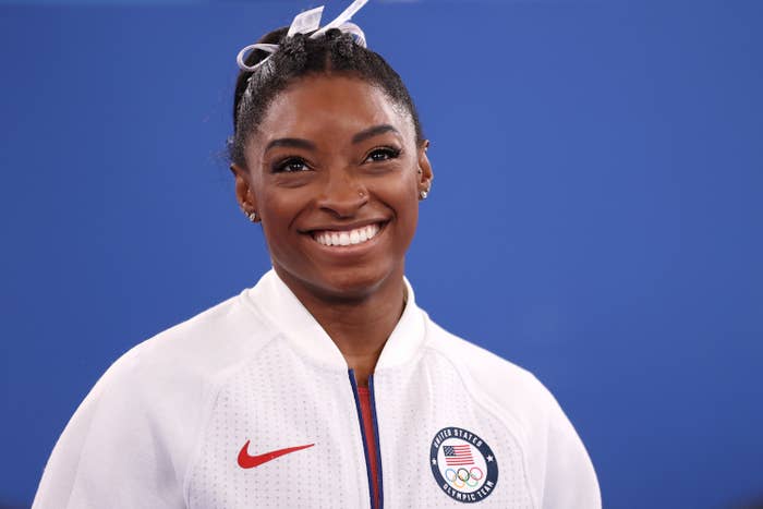 Simone smiles while wearing an Olympic jacket