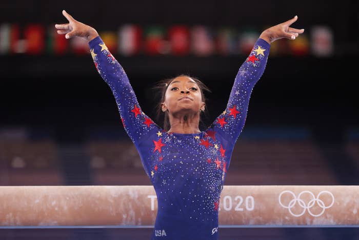 Simone poses with her arms stretched above her head after performing on the balance beam