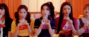 Red Velvet sits together on a table and drink a cocktail from a bag