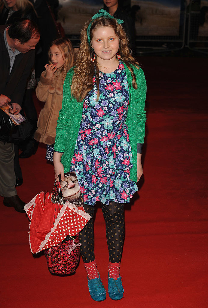 Jessie posing on a red carpet in a floral-print dress and tights