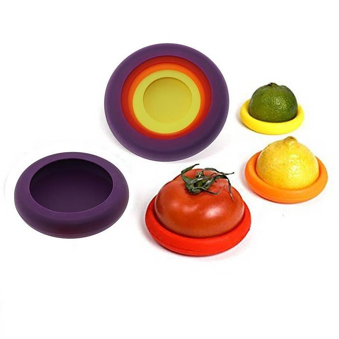 Purple, red, orange and yellow silicone food savers with a halved tomato and a halved lemon