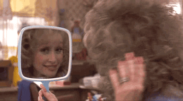 Dolly Parton fixes her hair in a handheld blue mirror in Steel Magnolias