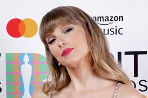 Taylor Swift poses with her hand on her hip at a red carpet event while wearing a two-piece outfit