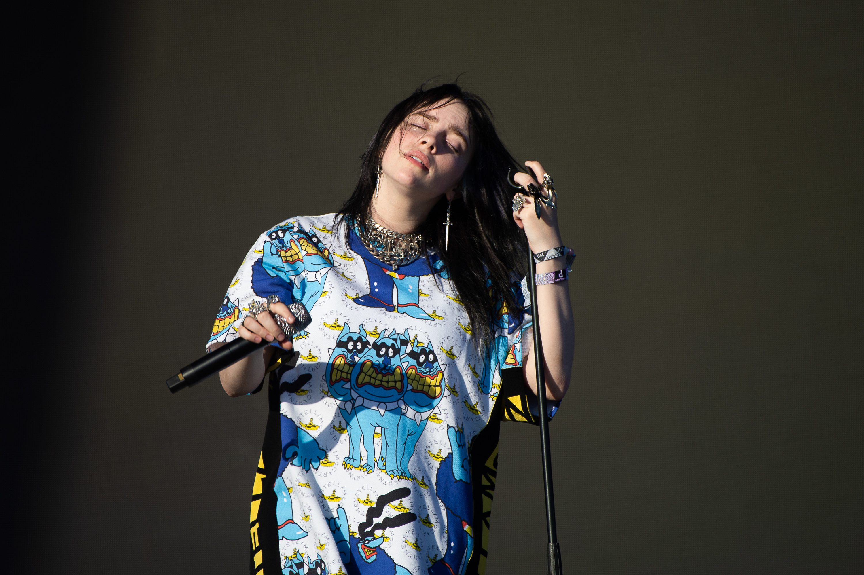 Billie performing onstage with her eyes closed and her hands on two microphones