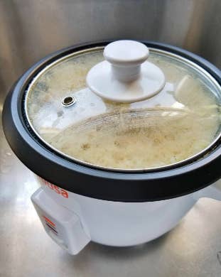 reviewer's rice cooker cooking with the lid on 