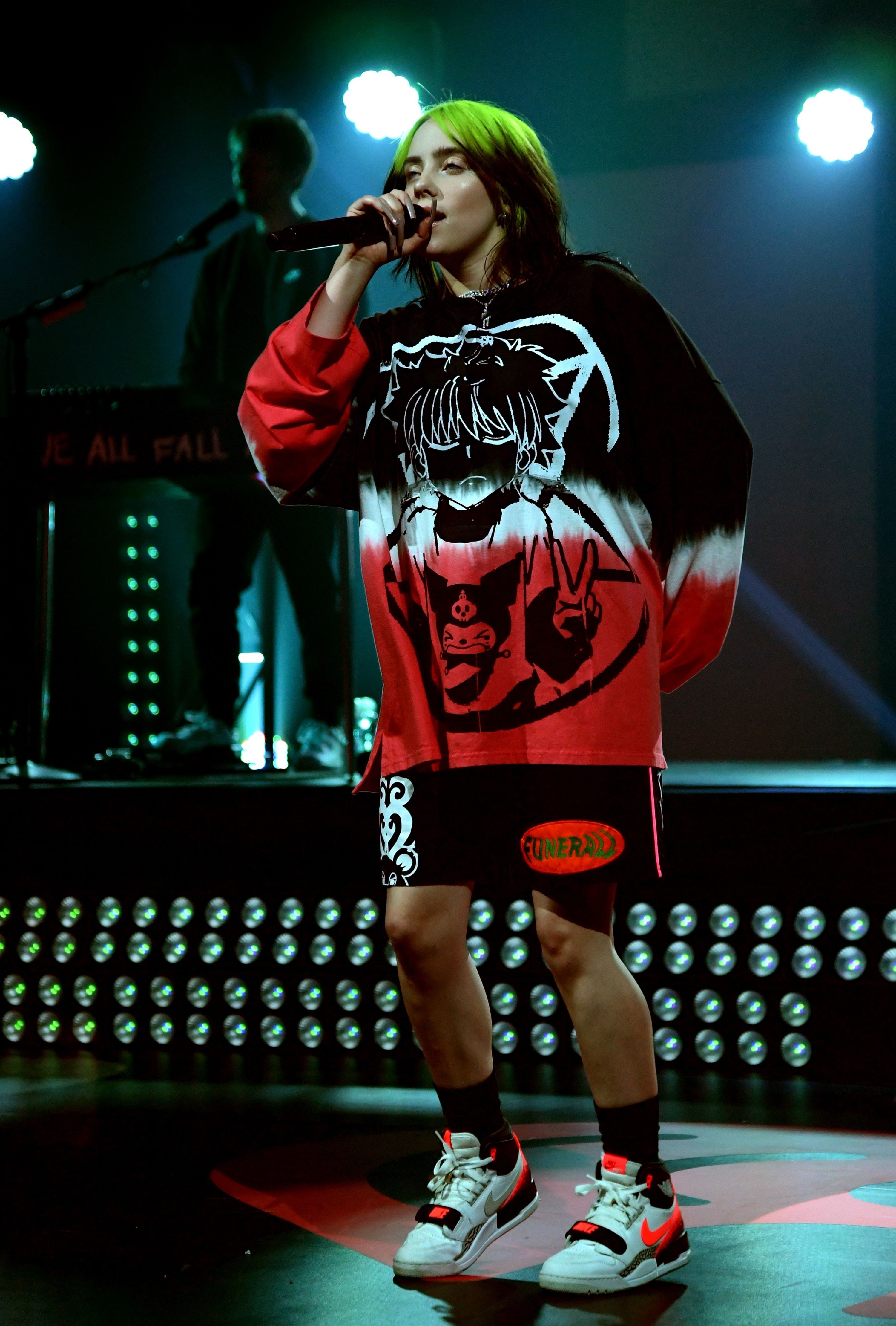 Billie performing in sneakers, shorts, and loose-fitting, long-sleeved top