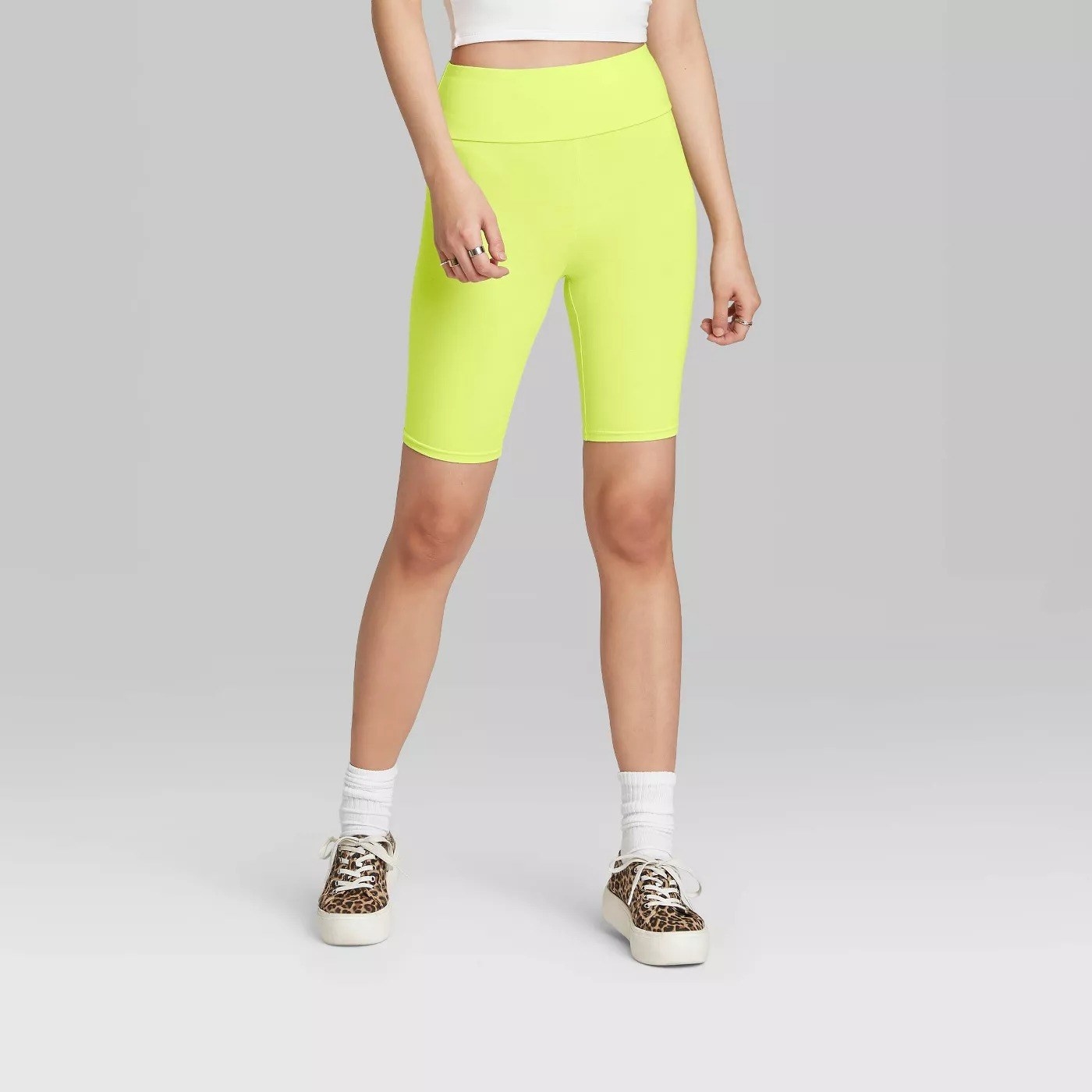 Model wearing tight  neon yellow shorts, stop above the knee
